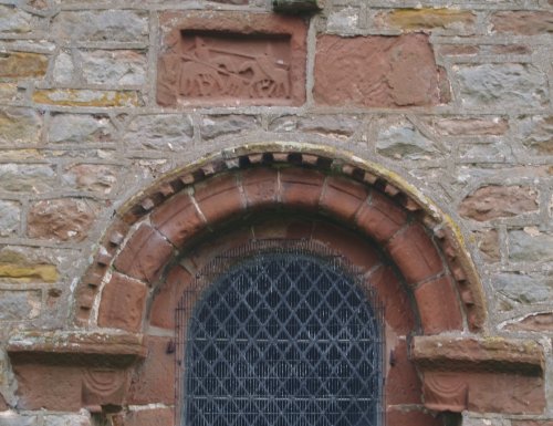All Saints Church  early Norman sandstone carving in the north wall. Note the two knights jousting above the old doorway. - River Eden walk, Bolton Village near Appleby, Cumbria, Northern England