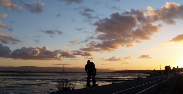 The Dublin sunset over the power station seen from the Clontarf-Sutton Cross road as a skate boarder flashes by!