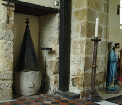 The medieval font with a curious hood on it.