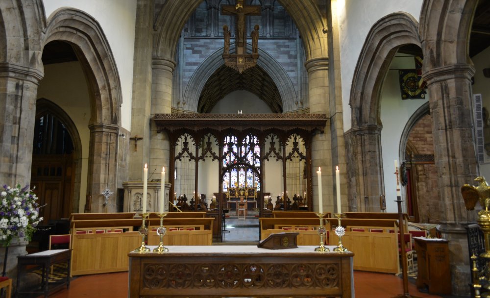 Looking towards the altar frontal (four candles), rood screen (designed by Oldrid Scott) chapter stalls of the choir, altar and east window of Saint Deiniol's Cathedral, Bangor, North Wales