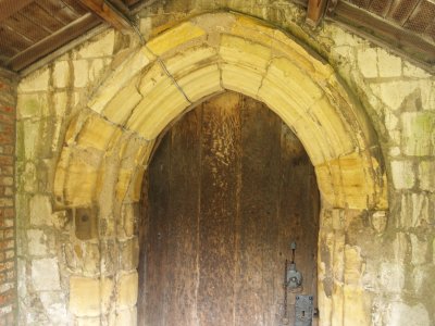 The west, and main entrance doorway, holding a very old wooden door.