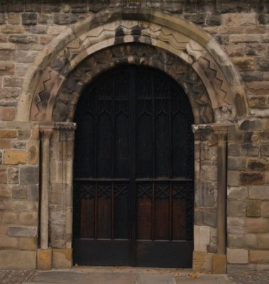 The west doorway, much eroded and much restored but one of the few clearly visible features of the original Norman church.