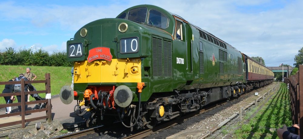 Class 37 diesel locomotive D6700 carrying the head board THE ROBIN HOOD, leaving Quorn and Woodhouse station with a passenger service from Loughborough Central to Leicester North, Great Central Railway heritage weekend Gala 'Railways at Work' (GCR August 2023)