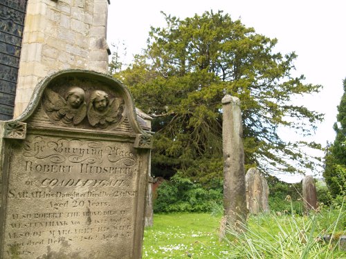 The remains of an old 7th century Saxon cross stands outside the east end of the church, with the ancient yew tree in the background.