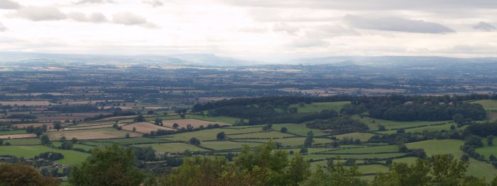 The rich agricultural land below the Vale of York and the outline of distant hills of the Yorkshire Dales and Pennines. - Walking from Sutton Bank National Park Visitor Centre, North York Moors National Park, North Yorkshire, Northern England