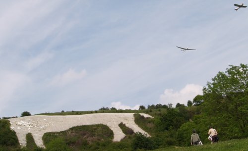 The piper light aircraft towing one of the gliders out and upward above the White Cross of Kilburn.