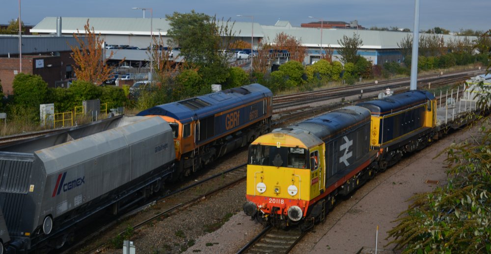 GBRf Railfreight EMD locomotive Class 66/7 66758 (blue/yellow livery) hauling a CEMEX cement train passed the yard of UK Rail Leasing at Leicester